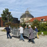 Das vierteilige Welle-Gestell wird vom Reinigergebäude auf den Platz getragen